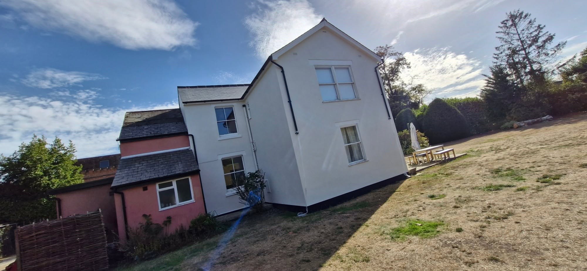 Side elevation of a white-rendered house under a blue sky