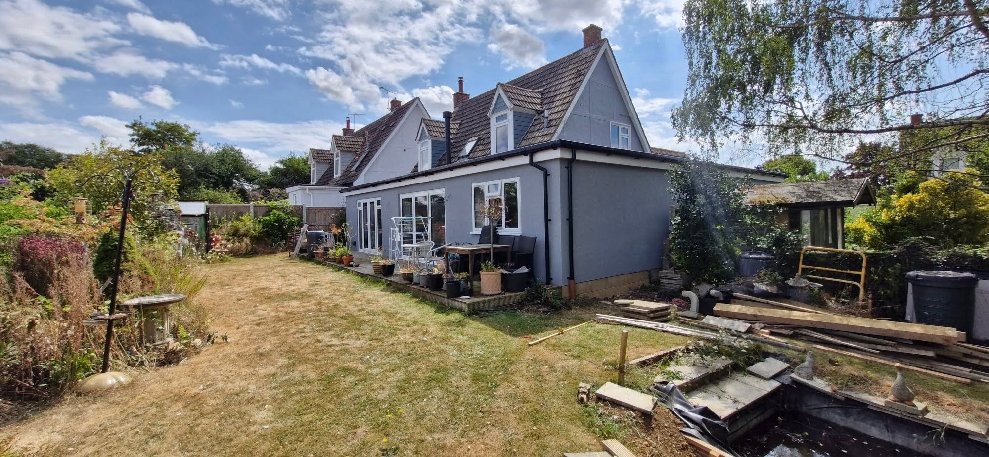 Grey-painted weatherboard bungalow seen from the back garden