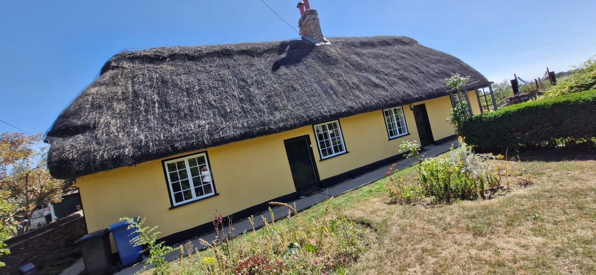 Thatched cottage with ochre walls and a black plinth