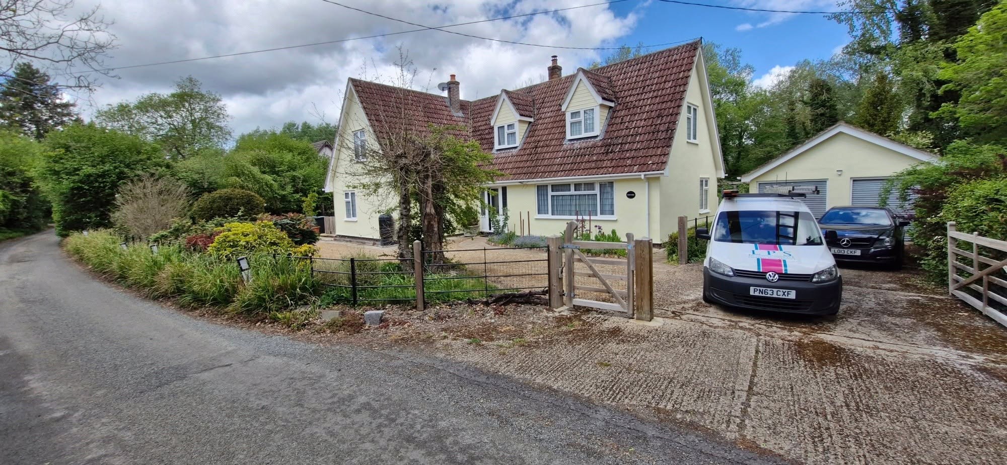 Cream chalet house seen from the lane with the LPS van parked outside