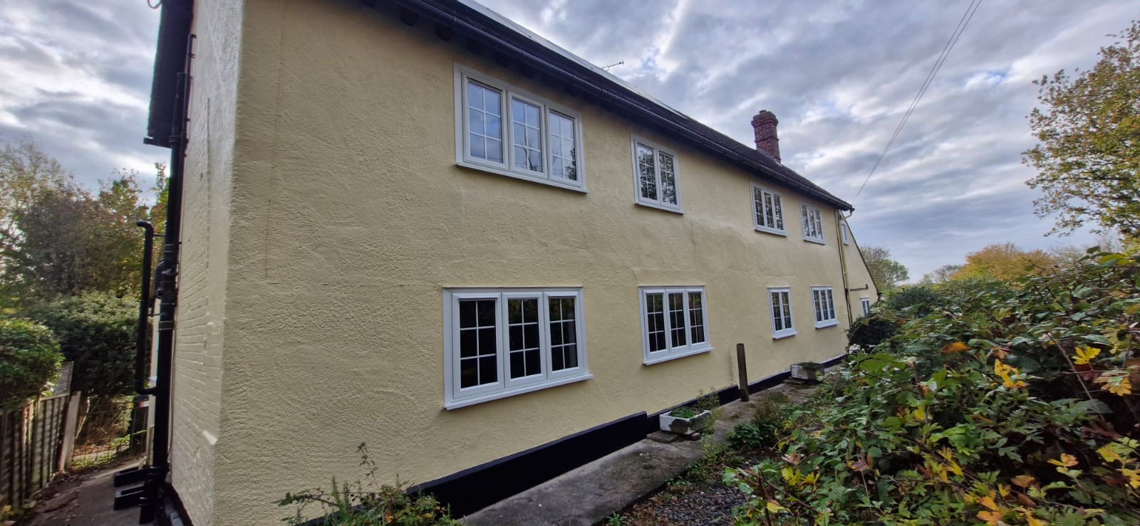 Long cream-rendered side wall with white windows