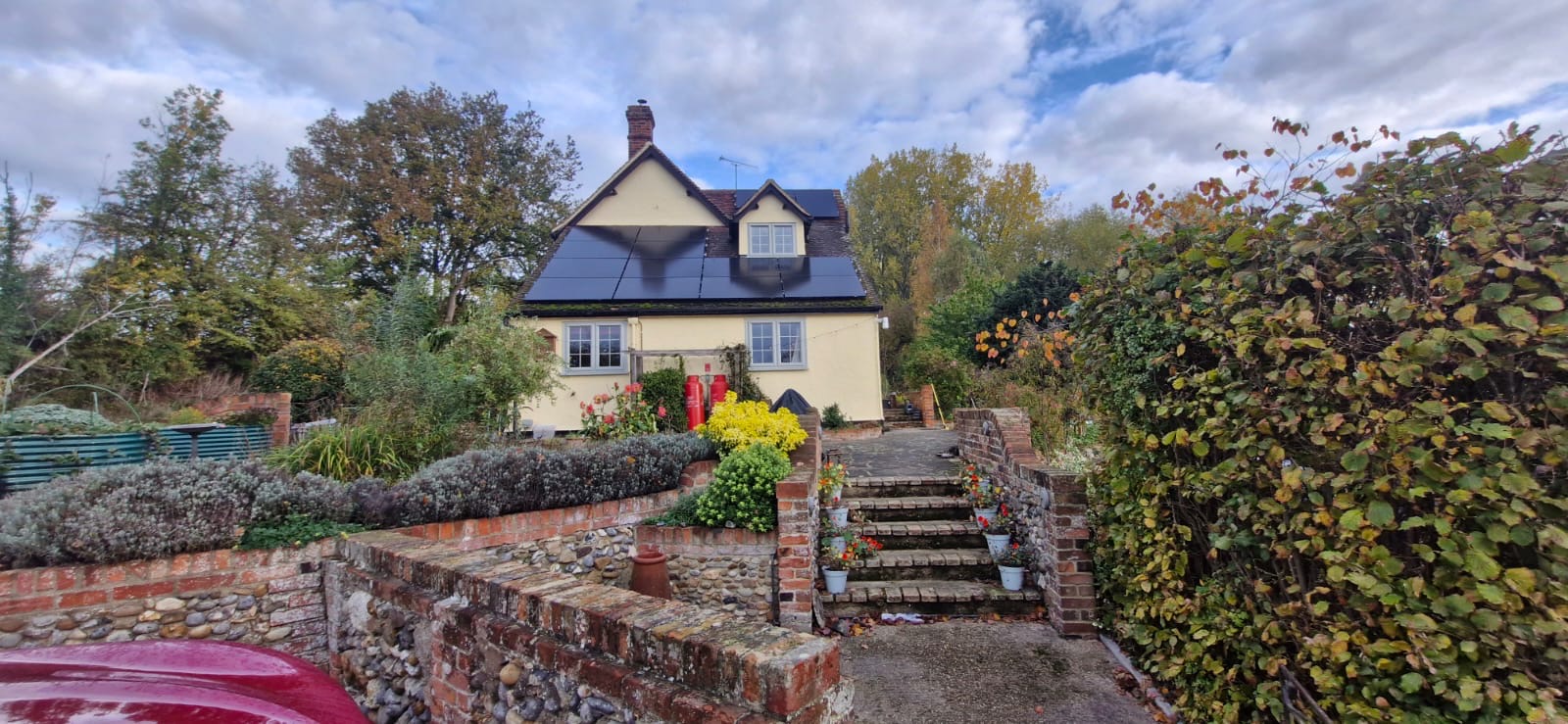 Cream cottage with solar panels above brick and flint garden steps